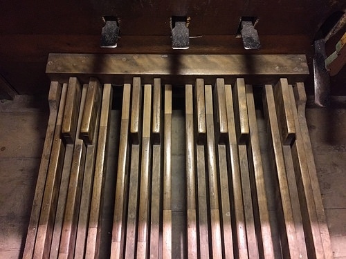 Performing in public or practicing upon a fine, early, historic pipe organ equipped with a diminutive pedalboard (photo) or perhaps no pedals altogether poses a special challenge.
One can tell a pedalboard is early and historic when the pedal keys are 1) parallel (non-radiating), 2) flat with the floor (non-concave), 3) short (compared with modern instruments), and 4) of limited compass (often less than 2 octaves) ... characteristics which generally make it impossible, for all practical purposes, to perform much of the baroque, classical, romantic, and modern contemporary repertoire upon them.
Many fine organs were built during the early 19th century with only one manual and no pedalboard at all, or, if they did have one, it might have been only one octave long chromatically, as from A1 to Ab2.
This is one of many situations where having learned some pieces written for pipe organ manuals only, or with limited pedal, can come in especially handy [See menu bar, Free Stuff, 2 Staff].
Pipe organs, especially older, historic instruments, compared with pianos, come in a huge variety.
From our view as organists, it's much more challenging to play on different instruments than it is for a pianist to switch from one piano to another.
Pianists, if we ask them, will definitely disagree with that, but it's nevertheless true that the difference between pipe organs is greater than the difference between pianos.
One look at this pedalboard (photo) is enough to drive home this point; just with the pedals alone, no pianist is faced with such a wide diversity of shapes and sizes ...  whether they're flat or concave, straight or radiating, full compass or limited compass ... as the organist does.
Also, unlike the piano, new pipe organs designed as identical copies of precious, historic instruments have to be played differently, and sound differently, in a different acoustical environments.
