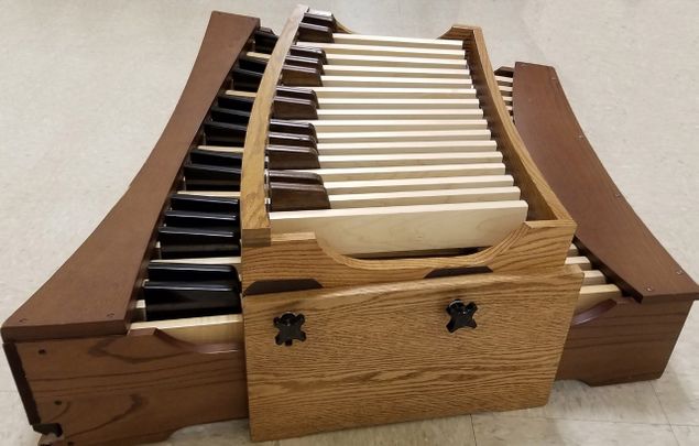 The concept of the Organ Pedal Booster (photo) was developed in 2016 by Nora Hess and Dr. Don Cook to allow very young children to play the pedals on the organ.
The strategy behind it is to make it practical for children to begin learning music at the organ from the very beginning (note reading, technique, improvisation, easy organ pieces and hymns, etc.).
It hovers above a standard AGO pedalboard bringing the keys over 6 inches closer to young feet.
Its weight is suspended by 2 outer supports that rest on the floor, enabling the Booster's 28 keys to gently depress the host pedal keys with felt-tipped dowels.
Spring tension for each key is still controlled by the host pedalboard as the Booster keys rest lightly on top.
The entire Booster pedalboard adjusts up and down, and each dowel is also adjustable.
This unit has a red oak frame in an oak finish with hard maple naturals and solid wood sharps.
Since 2017 the Brigham Young University Organ Department has been using this unit with positive results.
This unit is available for purchase through Ard Publications.