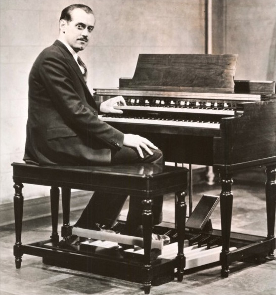 (con't from Part II)
Laurens Hammond (1895-1973), who is generally credited with the invention in 1934 of the Hammond electric organ and is shown in this photo seated at the ever popular Hammond Model B-3, was a mechanical engineer and one of the most famous inventors in history.
The Hammond organ, an instrument which, in some applications, is used in Godly praise and worship, was the product of the collaboration of Laurens Hammond and John Hanert and was first manufactured in 1935.
Although sometimes included in the category of electronic organs, the majority of Hammond organs today are, strictly speaking, electric or electro-mechanical rather than electronic organs because the sound is produced by moving parts rather than electronic oscillators. 
Until 1975 Hammond organs generated sound by creating an electric current from rotating a metal tonewheel near an electromagnetic pickup and then strengthening the signal with an amplifier to drive a speaker cabinet.
The basic component sound came from a tonewheel; each one rotated in front of an electromagnetic pickup, and the variation in the magnetic field incuded a small alternating current at a particular frequency which represented a signal similar to a sine wave; when a key was depressed on the organ it completed a circuit of 9 electrical switches which were linked to the drawbars; the position of the drawbars, combined with the switches selected by the key depressed, determined which tonewheels were allowed to sound.
Every tonewheel was connected to a synchronous motor via a system of gears which ensured that each note remained at a constant relative pitch to every other; the combined signal from the depressed keys and pedals was fed through to the vibrato system which was driven by a metal scanner; as the scanner rotated around a set of pickups it changed the pitch of the overall sound slightly; from here the sound was sent to the main amplifier and on to the audio speakers.
This kind of instrument makes technical compromises in the notes it generates; rather than produce harmonics that are exact multiples of the fundamental as in equal temperament it uses the nearest available frequencies generated by the tonewheels, with the only guaranteed frequency for Hammond's tuning being concert A at 440 Hz.
It's of interest that crosstalk or 